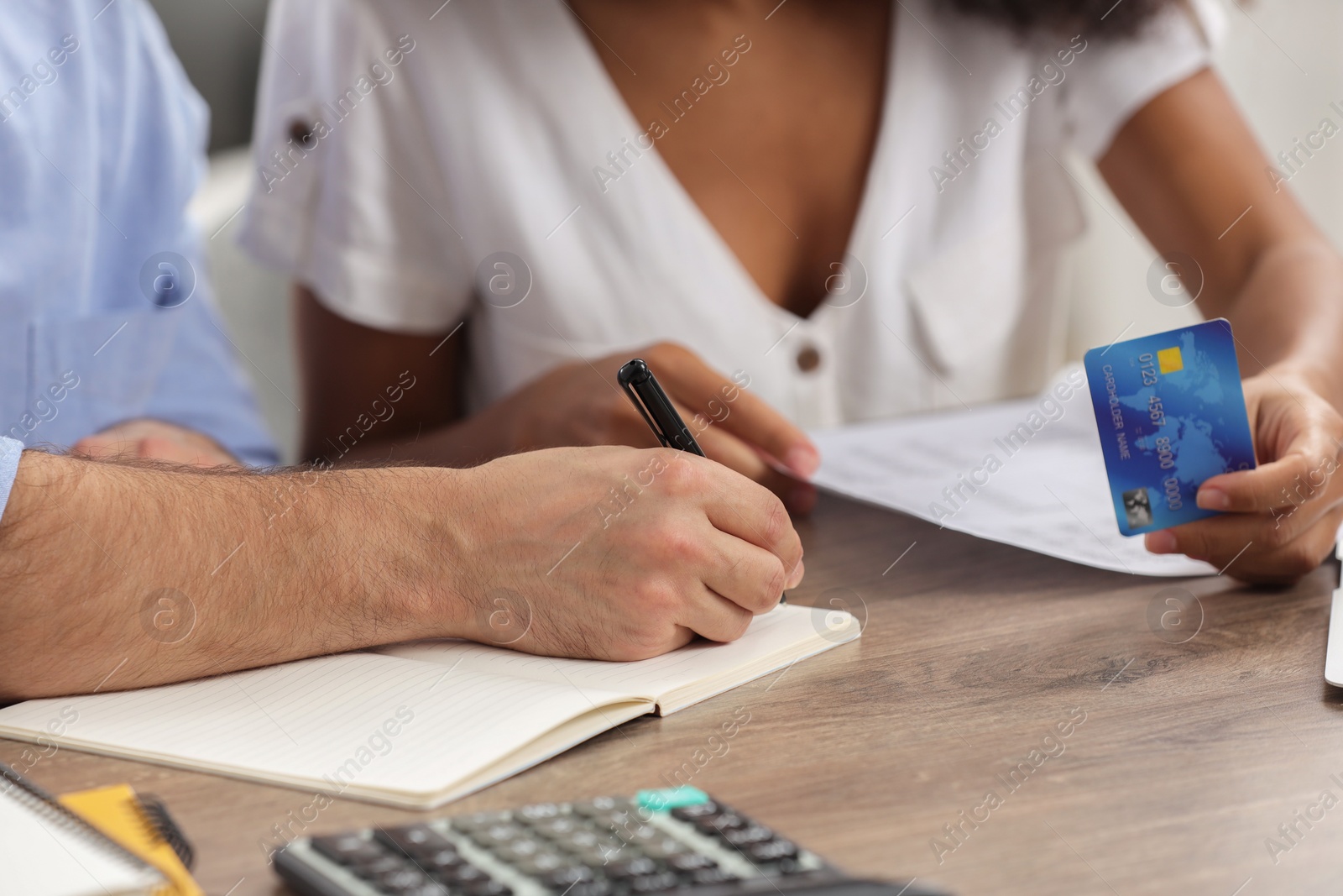 Photo of Couple with credit card planning budget at table indoors, closeup. Debt problem