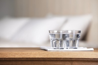 Photo of Glasses of pure water and napkin on wooden table indoors. Space for text
