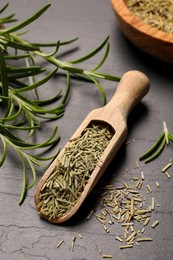 Photo of Wooden scoop with dry and fresh rosemary on black table