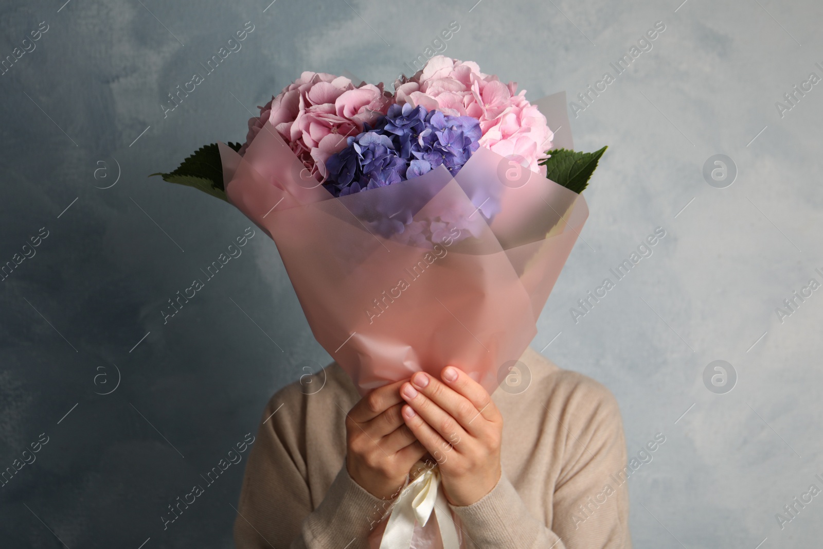 Photo of Woman with bouquet of beautiful hortensia flowers on color background