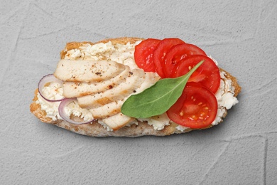 Delicious chicken bruschetta on light grey table, top view