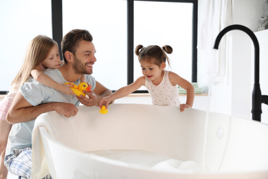 Photo of Young father with little daughters in bathroom