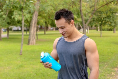 Photo of Man with bottle of protein shake in park. Space for text