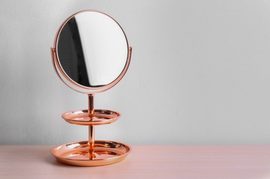 Photo of Modern mirror on table near color wall