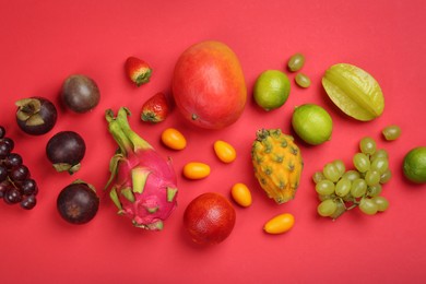 Photo of Many different delicious exotic fruits on red background, flat lay