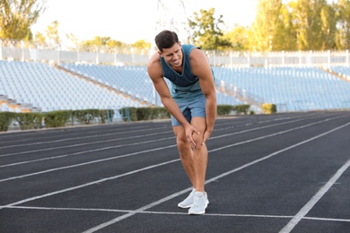 Photo of Man in sportswear having knee problems at stadium