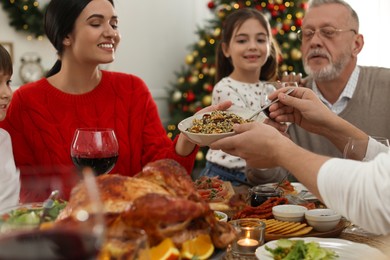 Photo of Man giving bowl of traditional Christmas kutia to woman at festive dinner, focus on hands. Slavic dish