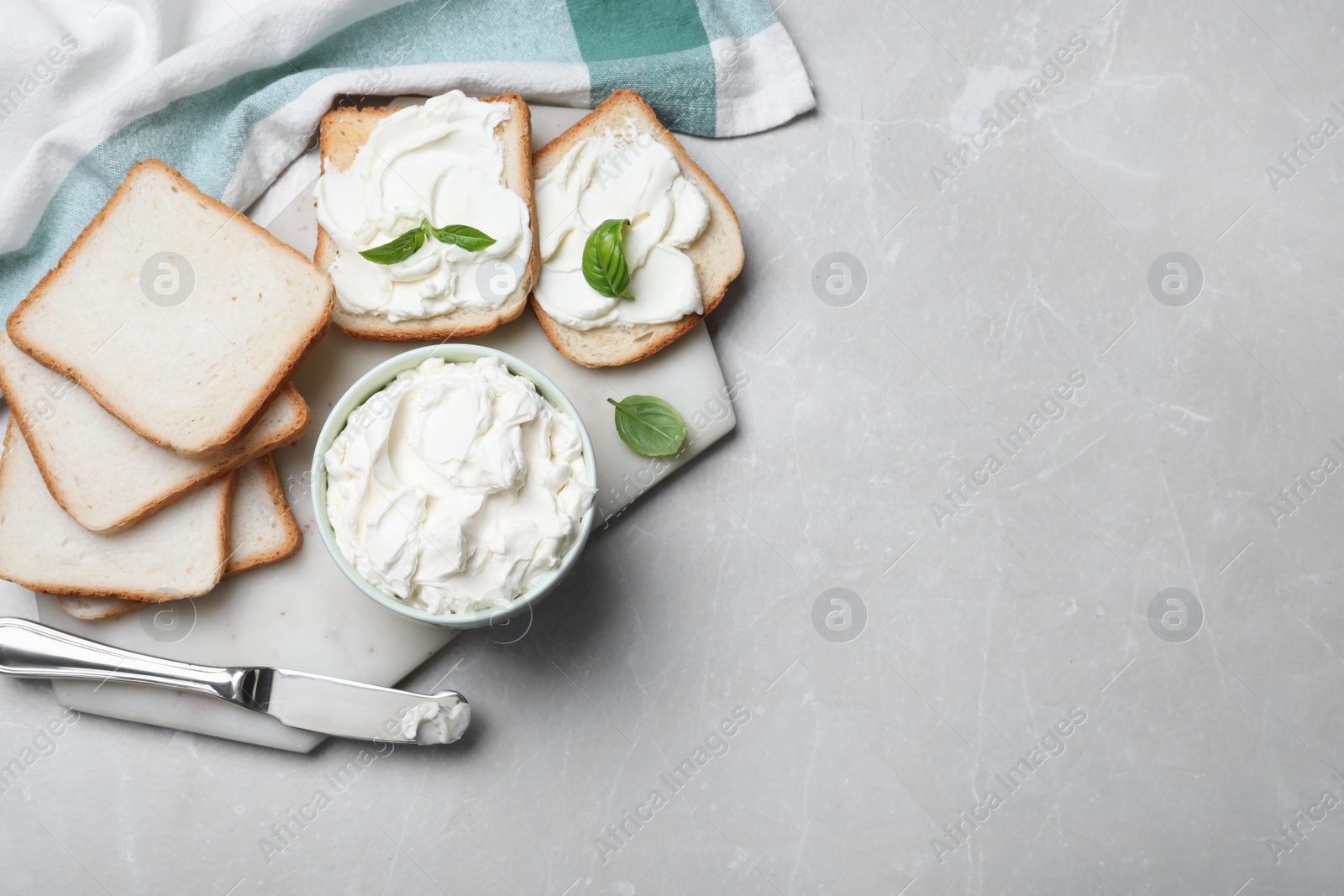 Photo of Fresh bread and delicious cream cheese on grey table, flat lay. Space for text
