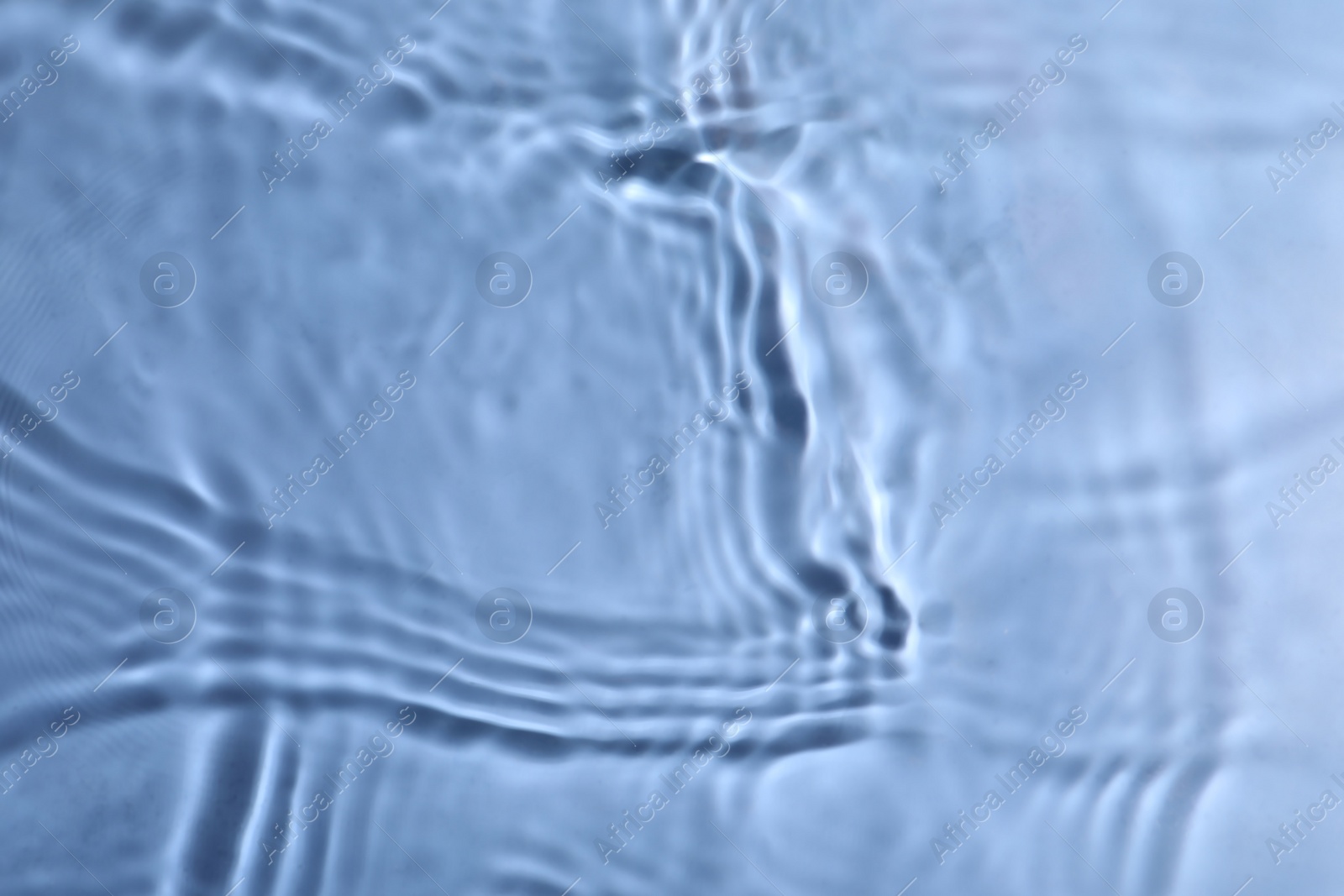 Photo of Closeup view of water with rippled surface on blue background