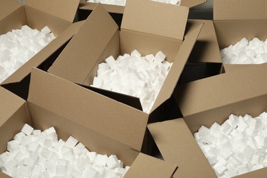 Photo of Open cardboard boxes with pieces of polystyrene foam on floor. Packaging goods
