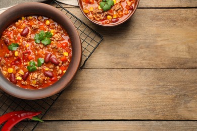 Tasty chili con carne on wooden table, flat lay. Space for text