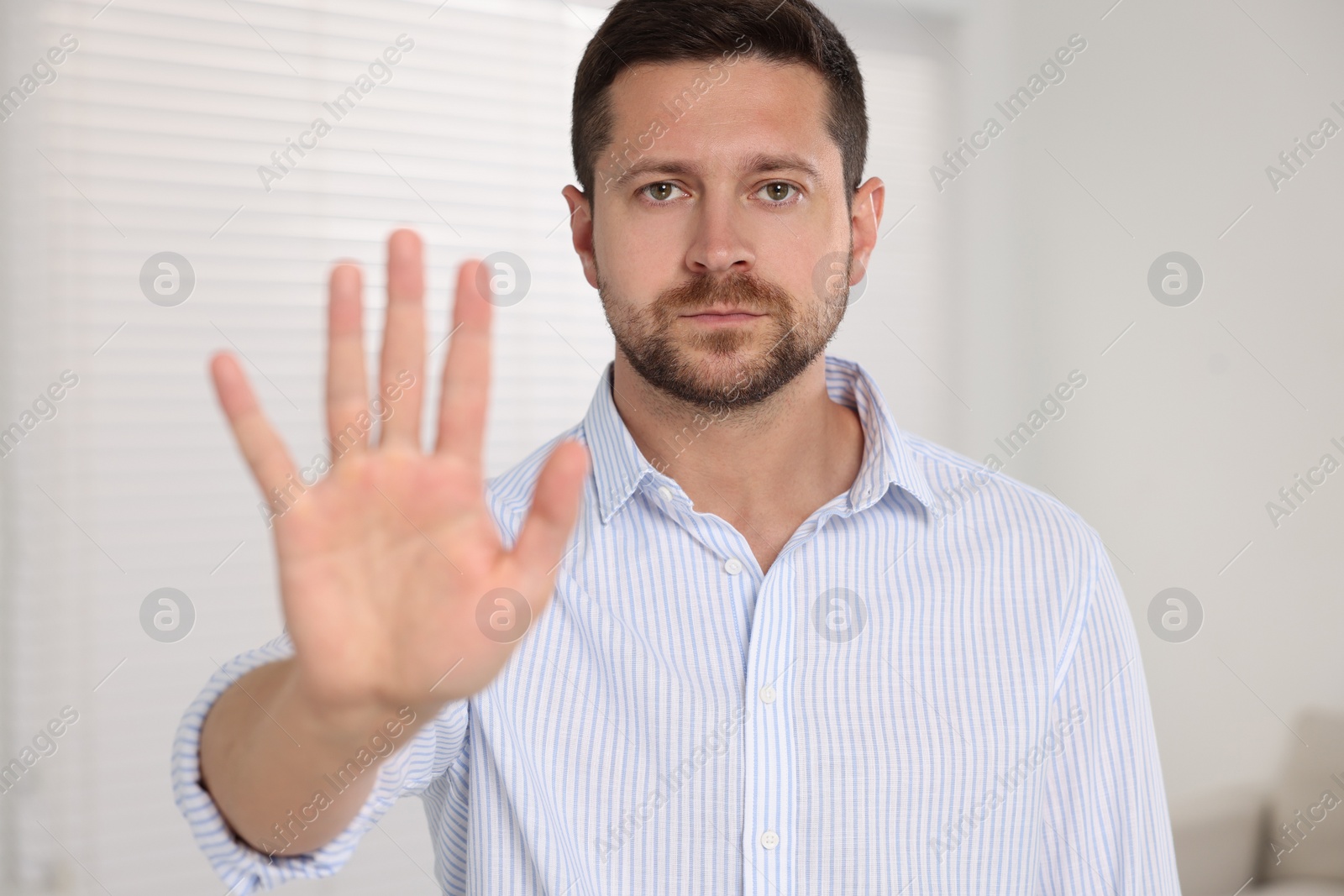 Photo of Handsome man showing stop gesture at home