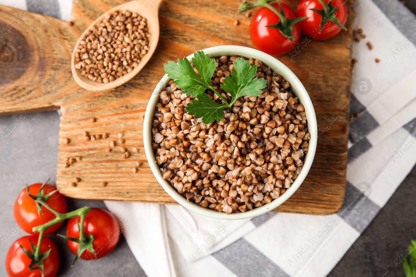 Photo of Flat lay composition with bowl of buckwheat porridge and tomatoes on table