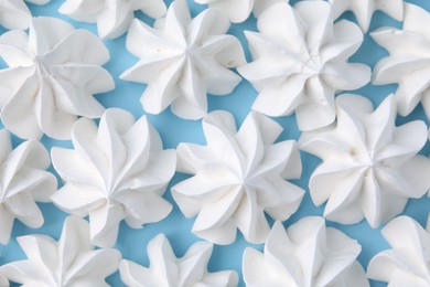 Tasty meringue cookies on light blue background, flat lay