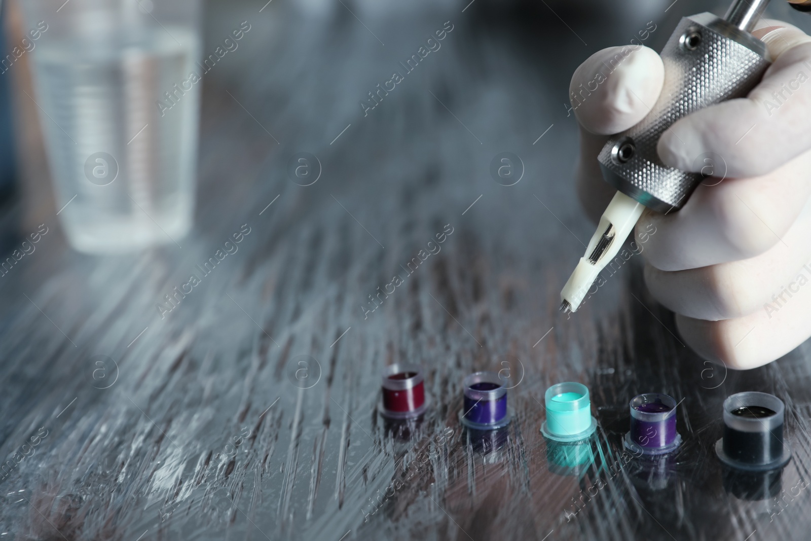 Photo of Tattoo artist with machine and ink at table, closeup