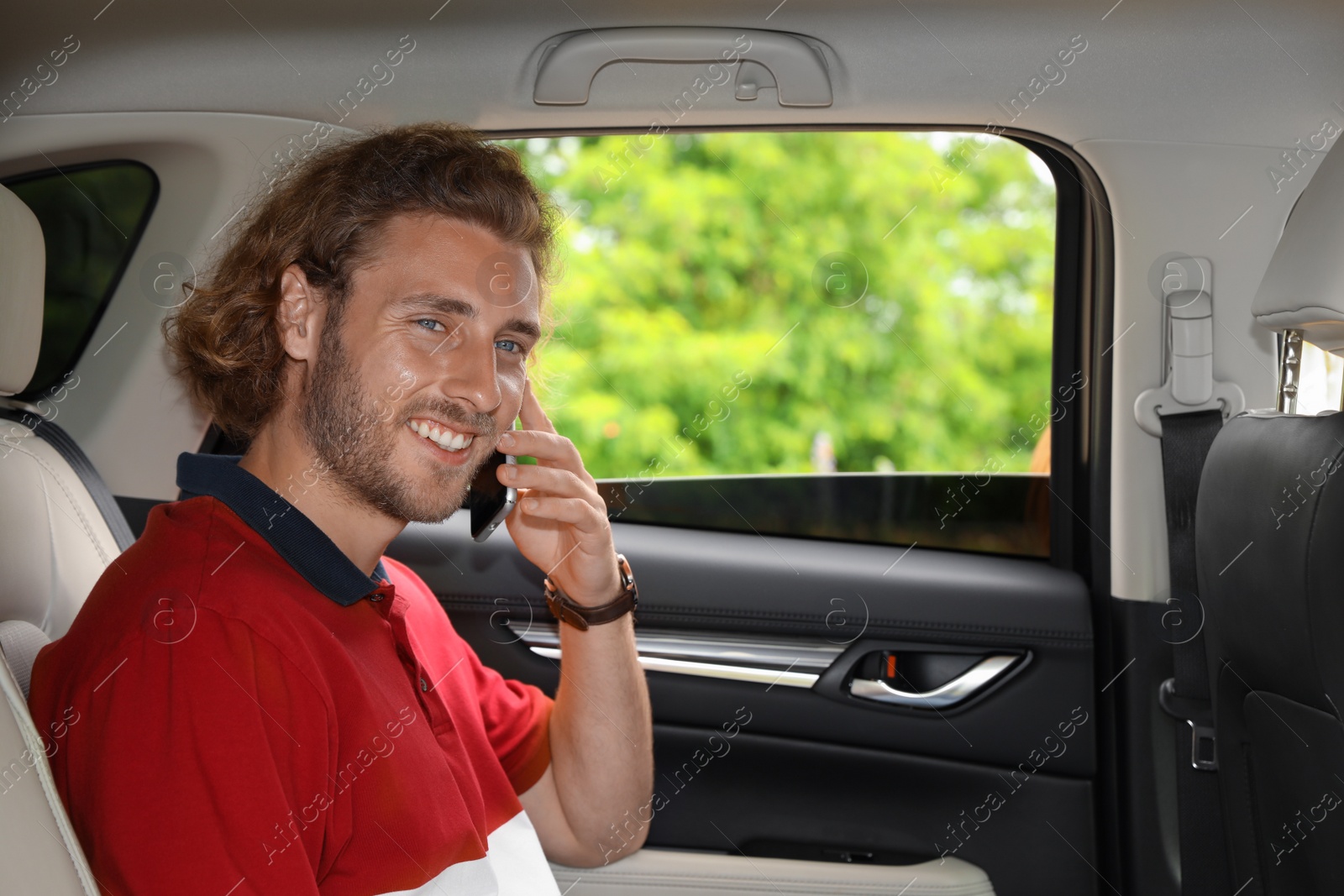 Photo of Attractive young man talking by phone on backseat in luxury car