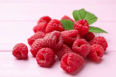 Photo of Delicious fresh ripe raspberries on pink wooden table, closeup view