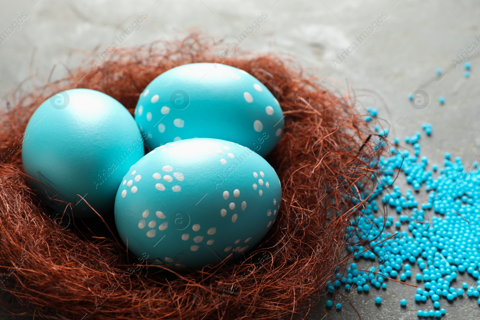 Photo of Sisal nest with painted Easter eggs on color background, closeup. Space for text