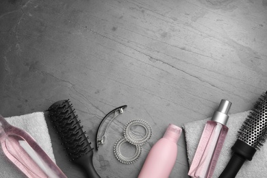 Photo of Flat lay composition with hair cosmetic products and tools on grey background. Space for text