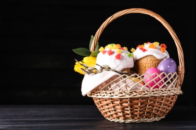 Photo of Traditional Easter cakes in wicker basket on dark background. Space for text