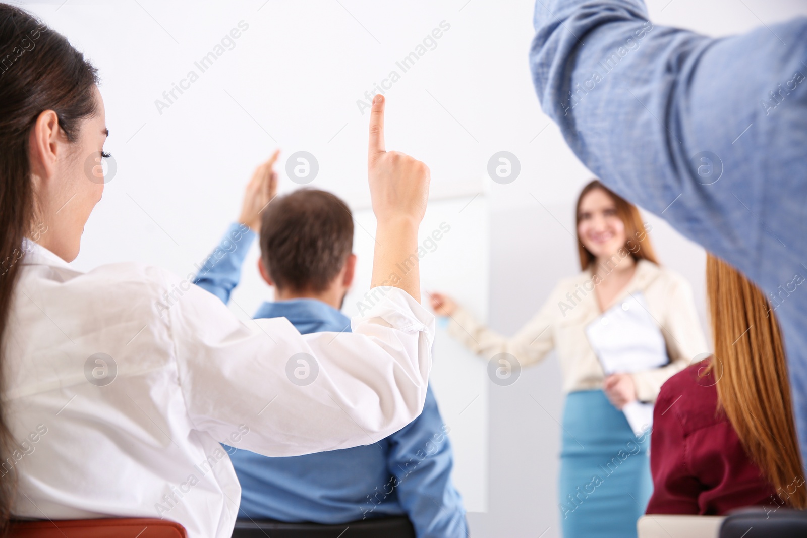 Photo of Young woman raising hand to ask question at business training indoors, closeup