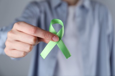 Photo of Woman with green awareness ribbon on grey background, closeup