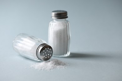 Photo of Natural salt in shakers on color background, space for text