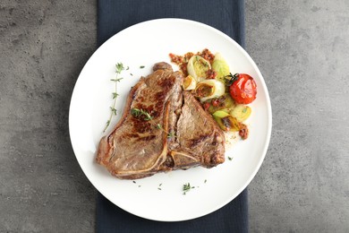 Delicious fried beef meat and vegetables on grey table, top view