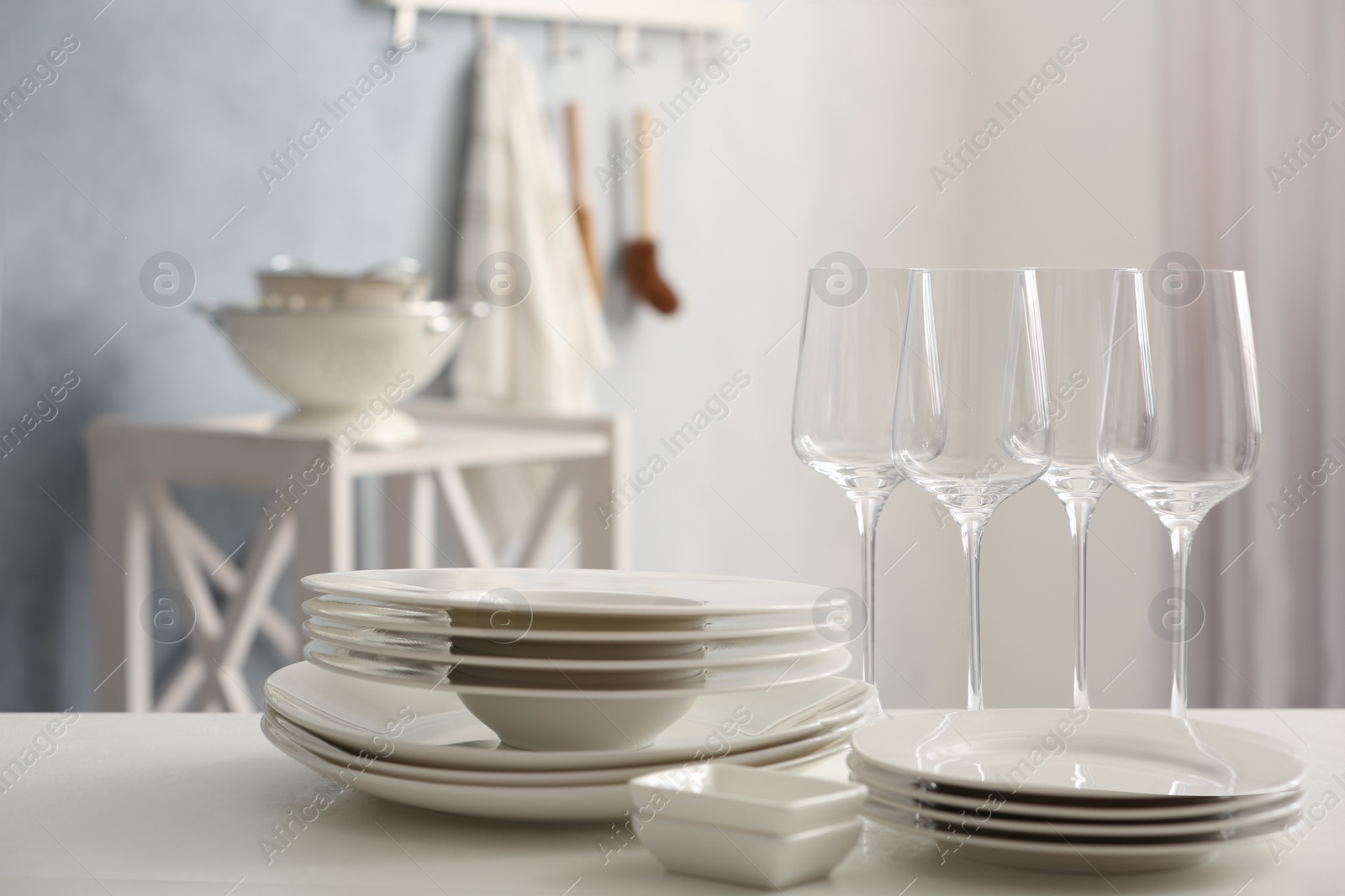 Photo of Set of clean dishware and wineglasses on white table indoors