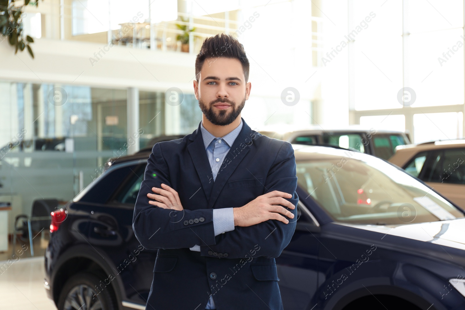 Photo of Young salesman near new car in dealership