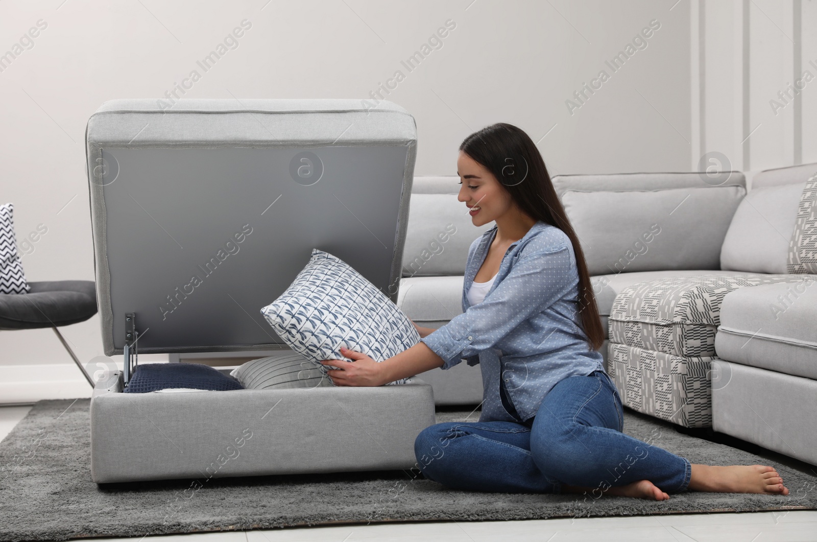 Photo of Woman taking soft pillow from modular sofa section in living room