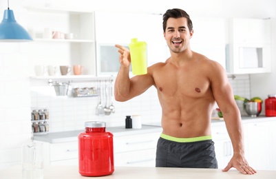 Photo of Young shirtless athletic man with protein shake powder in kitchen, space for text