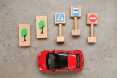 Miniature road signs, trees and car on grey table, flat lay. Driving school