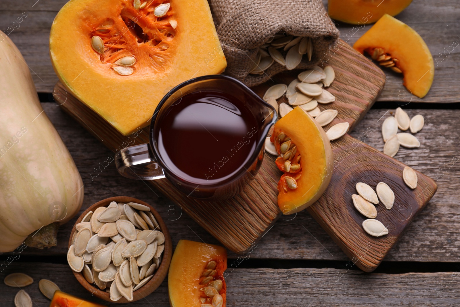 Photo of Flat lay composition with pumpkin seed oil in glass pitcher on wooden table