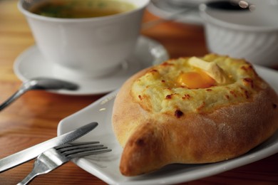 Photo of Fresh delicious Adjarian khachapuri with cheese and egg on wooden table, closeup