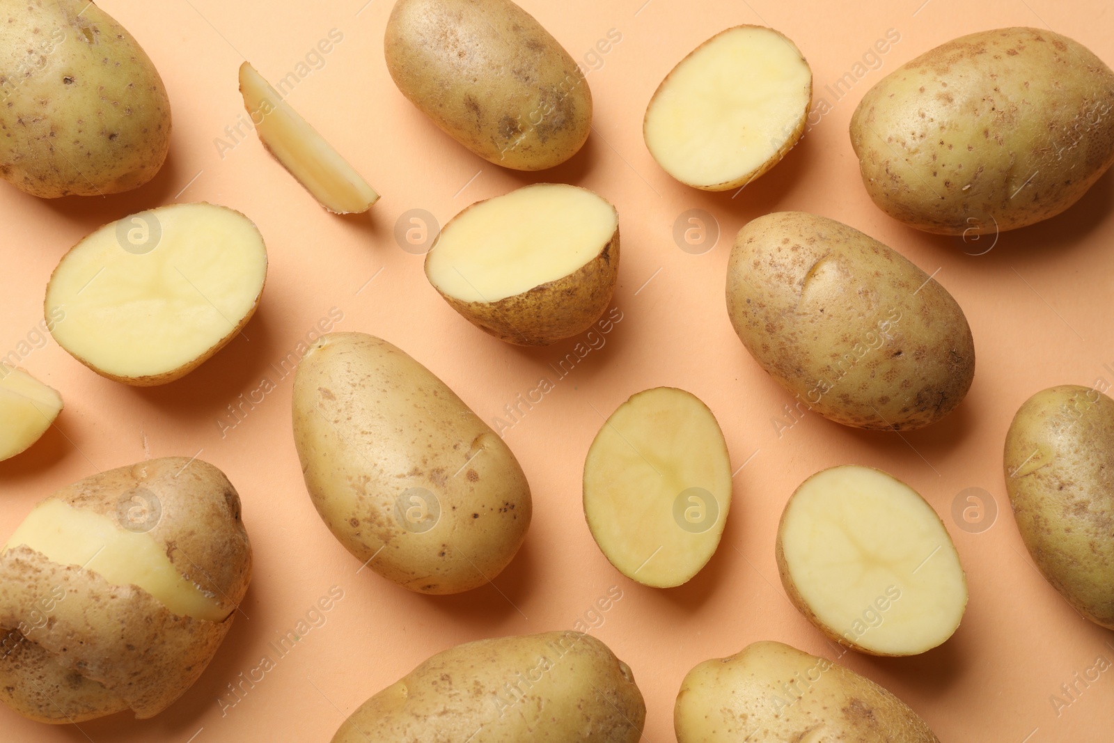 Photo of Fresh raw potatoes on pale orange background, flat lay