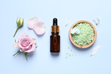 Photo of Bottle of cosmetic serum, beautiful flowers and sea salt on light blue background, flat lay