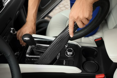 Man using vacuum cleaner in auto, closeup. Car wash