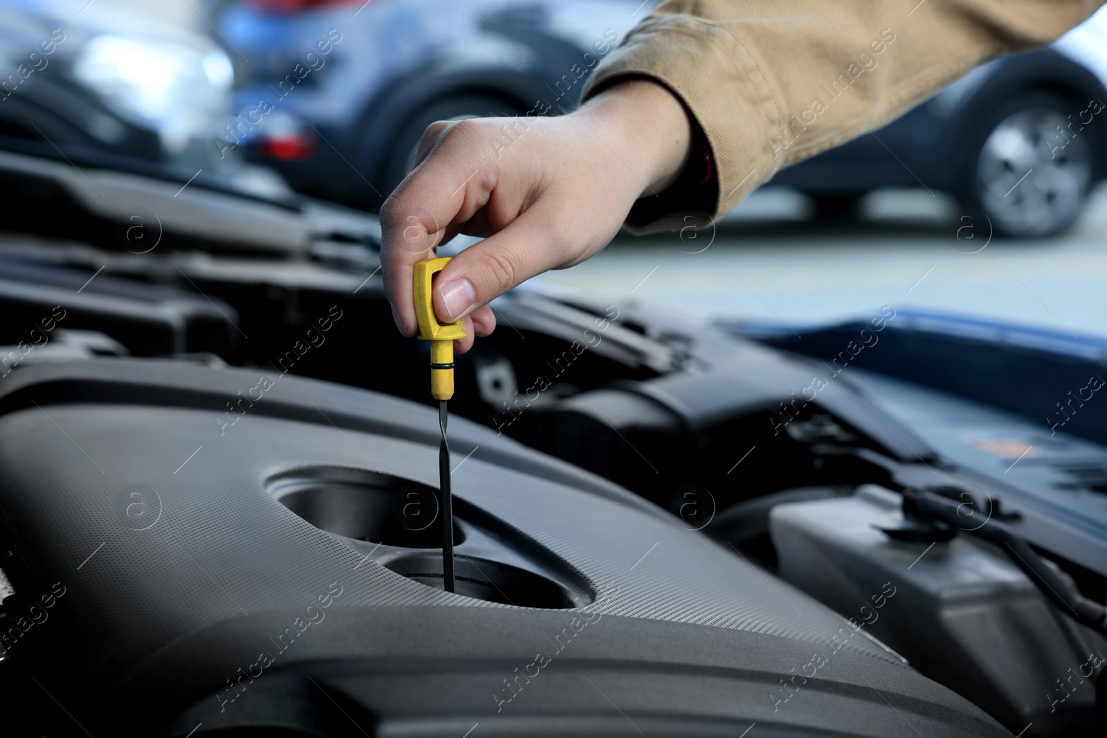 Photo of Man checking motor oil level in car with dipstick, closeup