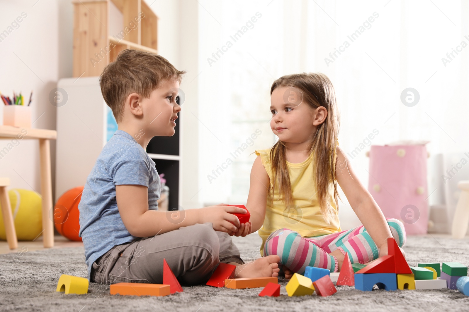 Photo of Little children playing with colorful blocks indoors