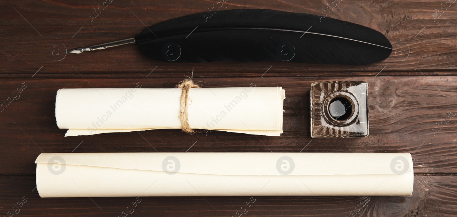 Image of Quill, inkwell and paper rolls on wooden table, flat lay. Banner design