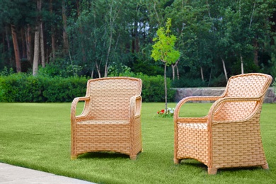 Photo of Garden rattan armchairs on green grass at backyard