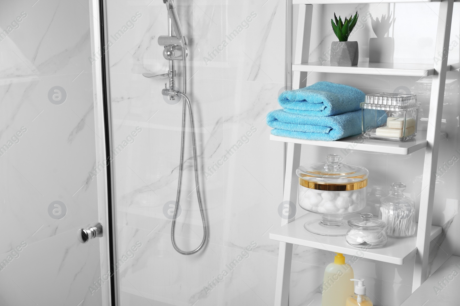 Photo of Shelving unit with cotton balls, swabs and pads in bathroom