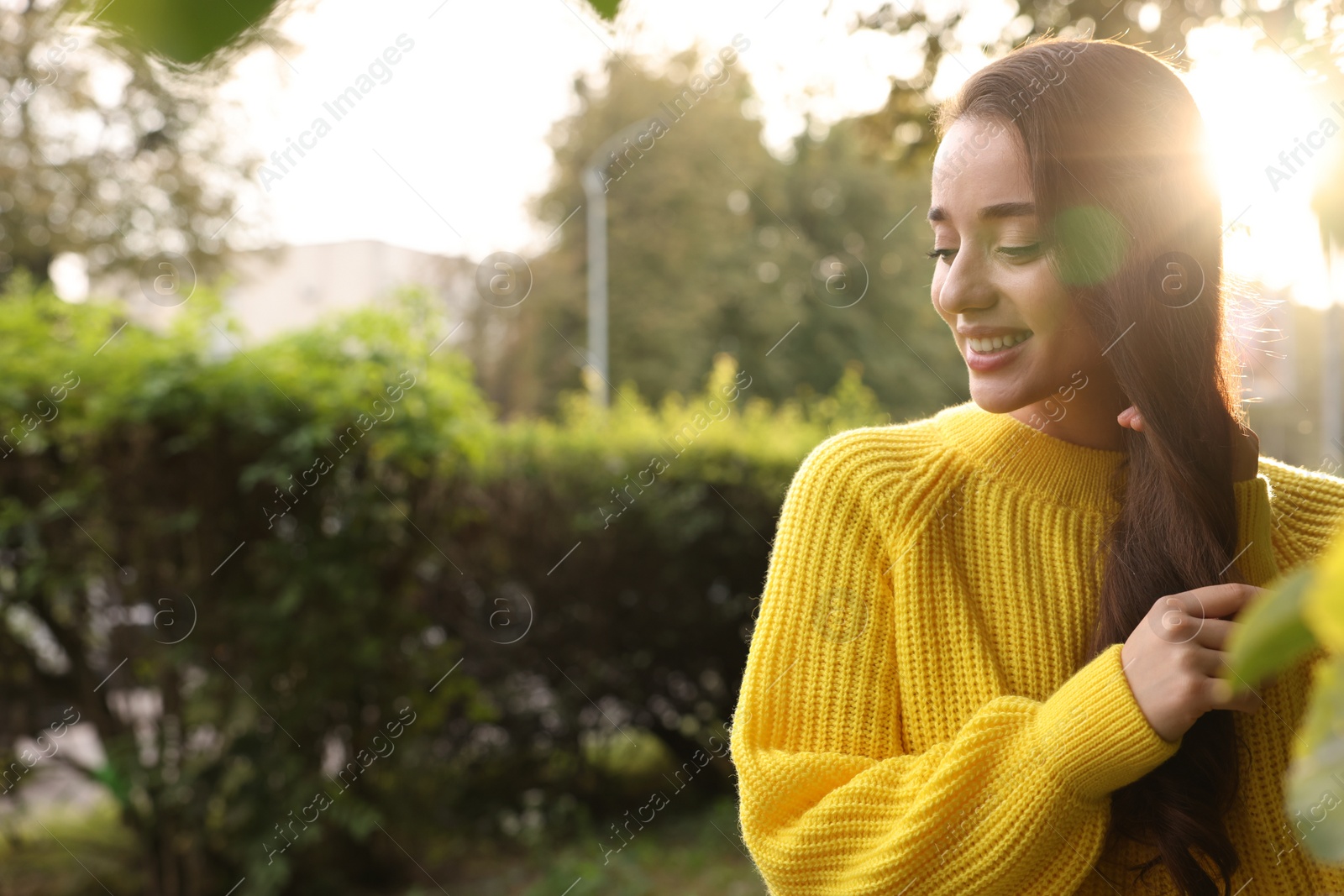 Photo of Beautiful young woman in stylish warm sweater on sunny day, space for text