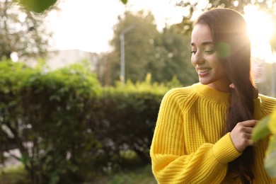 Photo of Beautiful young woman in stylish warm sweater on sunny day, space for text