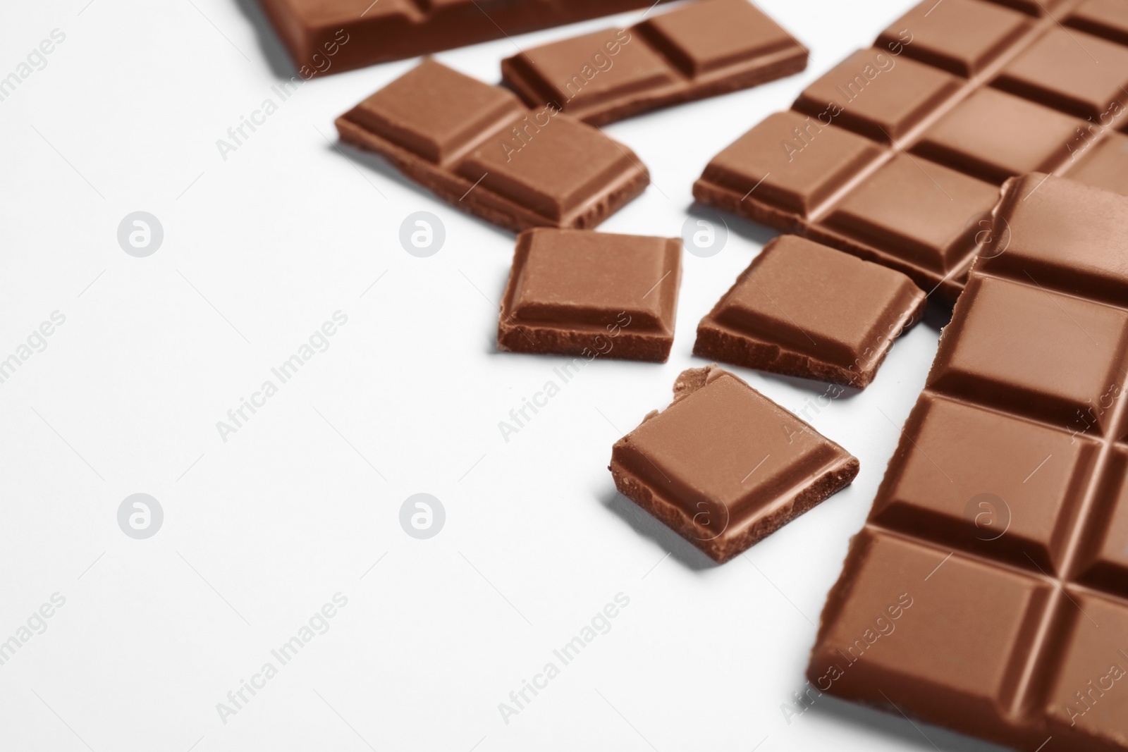 Photo of Pieces of delicious chocolate bar on white background, closeup. Space for text