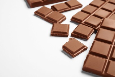 Pieces of delicious chocolate bar on white background, closeup. Space for text