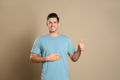 Photo of Happy healthy man touching his belly on beige background