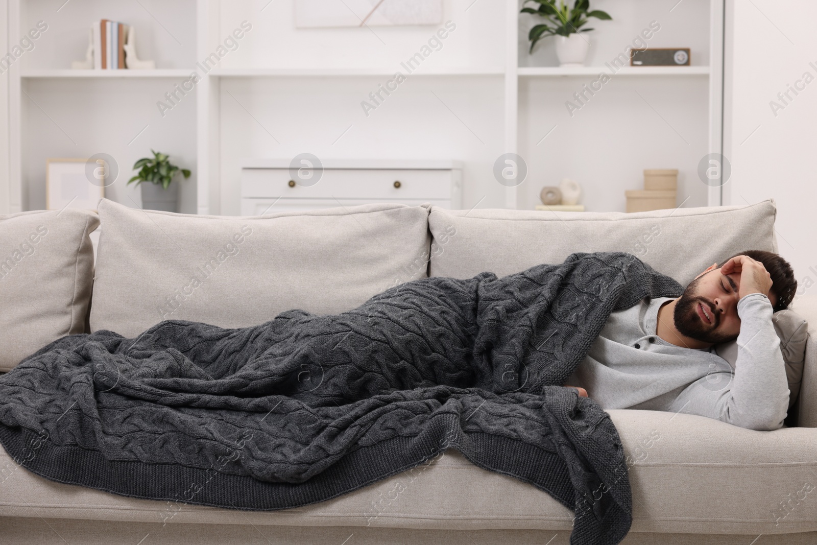 Photo of Man suffering from headache on sofa at home