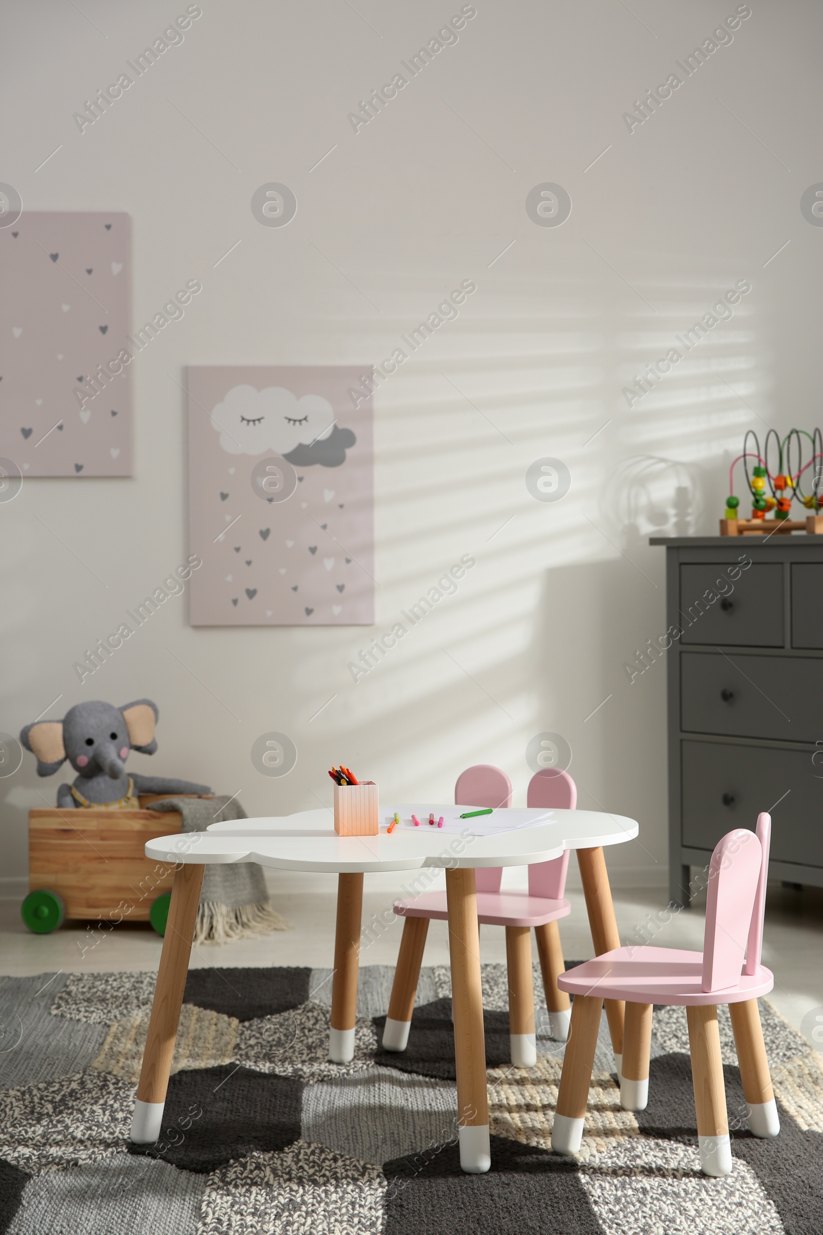 Photo of Little table and chairs with bunny ears in children's room. Interior design